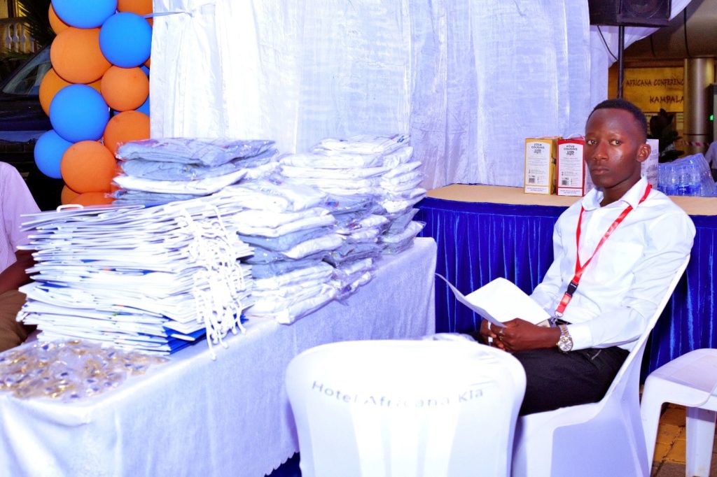 Mr. Asasira Derrick in charge of selling t-shirts and lapel pins during the alumni fundraising dinner at Hotel Africana.